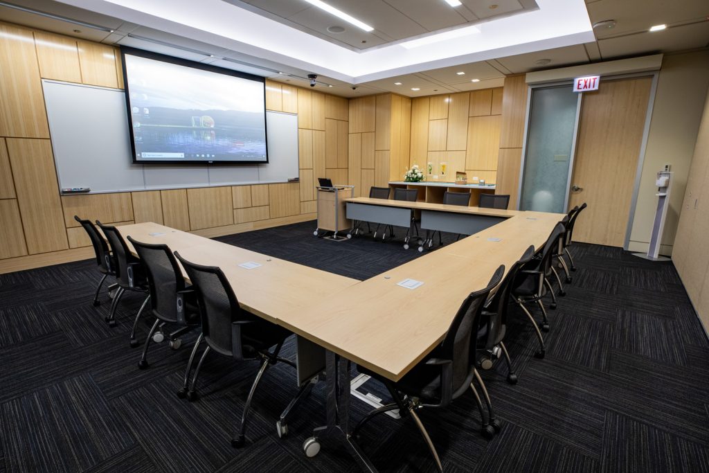 Conference Room 1C at One Rotary Place. Photo of a large conference room with tables &amp; chairs, a projector, and screen.