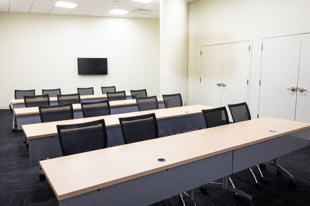 1st Floor Studio Conference Room at One Rotary Place. Photo of a small conference room with tables &amp; chairs and a flat screen TV.