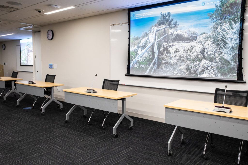 Conference Room 3AB at One Rotary Place. Photo of a section of a conference room with microphones and projection screens.