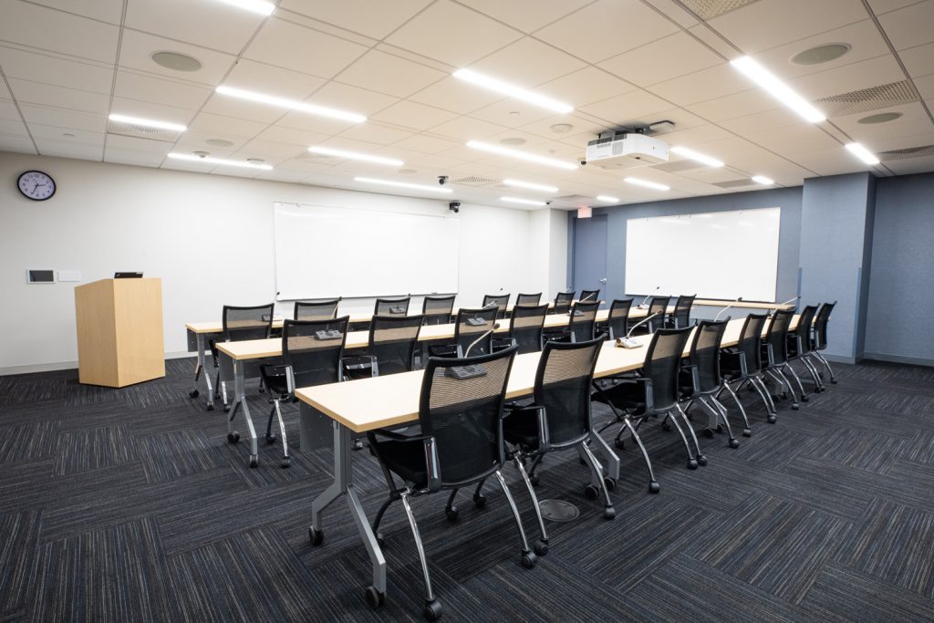 Conference Room 3A at One Rotary Place. Photo of a large conference room with tables &amp; chairs, a podium, and a whiteboard.