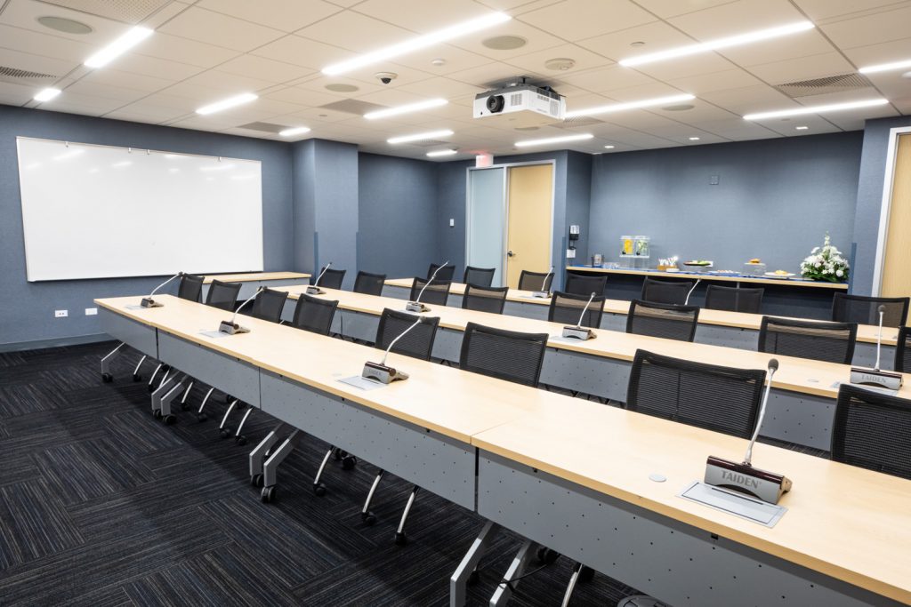 Conference Room 3A at One Rotary Place. Photo of a large conference room with tables &amp; chairs, a projector, catering, and a whiteboard.