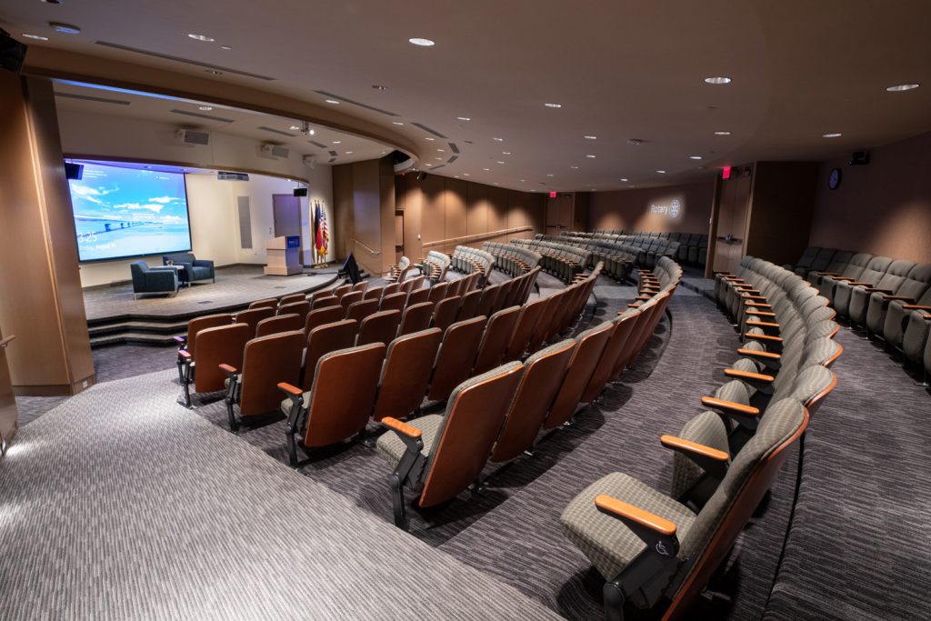 3rd Floor Auditorium at One Rotary Place. Photo of a large theater and stage featuring custom lighting and projections.